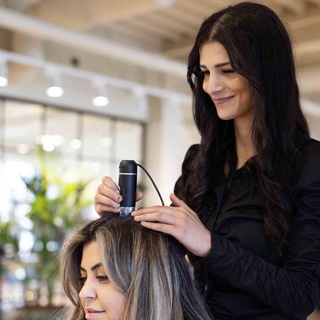 Employee from Zenz in Frederiksberg styles a customer's hair.